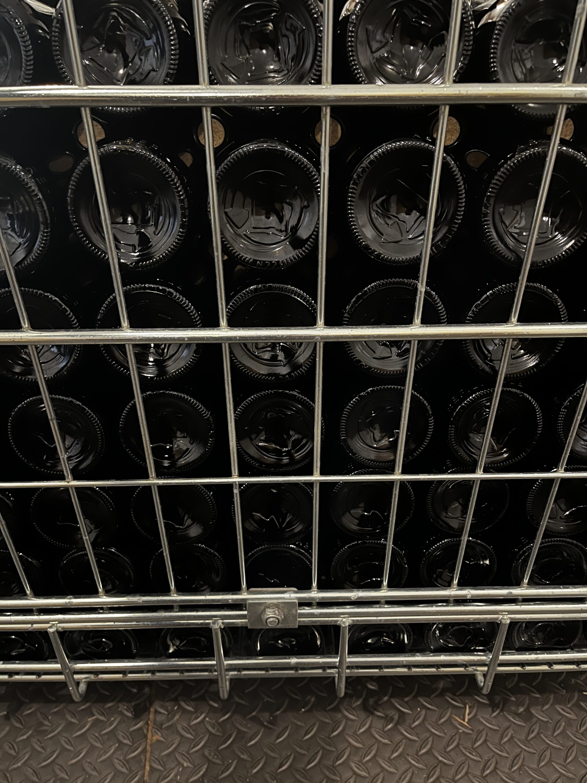 Close-up of stacked reusable glass bottle bases in a wire bin